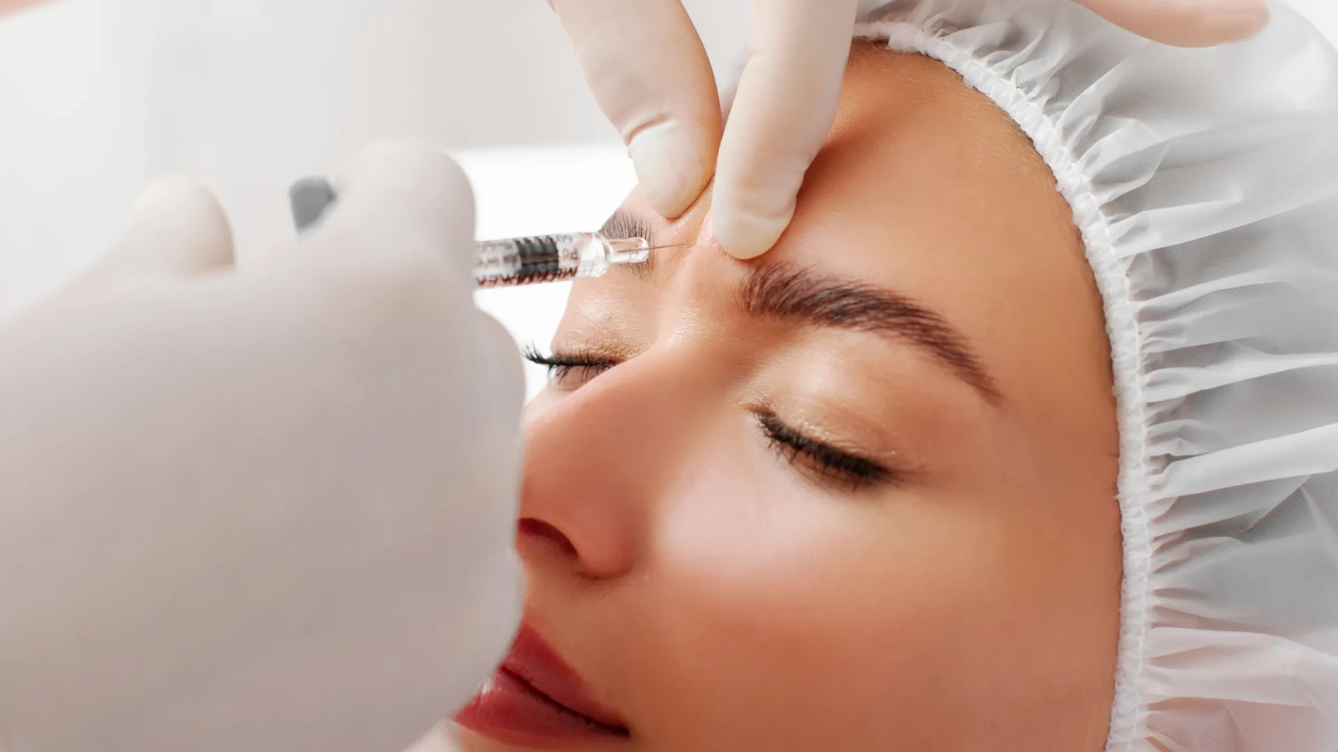 A clinician placing a precise neuromodulator injection near a guest's brow at No Ka Oi Aesthetics in Lahaina, Maui